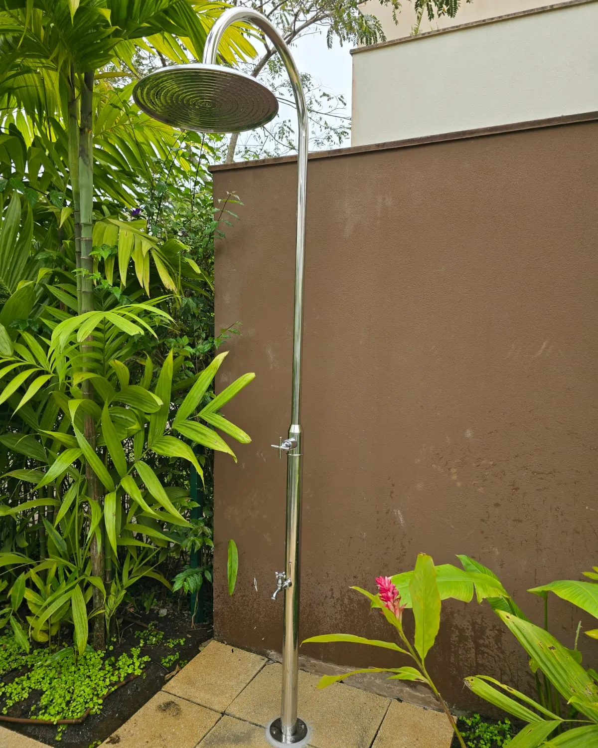 Ducha externa em inox desenvolvida sob medida pela Ketesi, instalada em jardim residencial