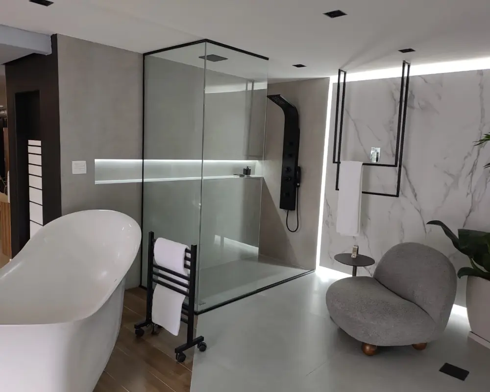Banheiro contemporâneo com banheira de imersão branca, toalheiro e box de vidro